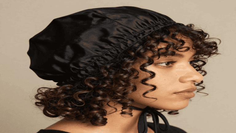 Woman with defined curly hair wearing a mulberry silk bonnet at night, showing how Silk Bonnets for Curly Hair help prevent frizz and breakage